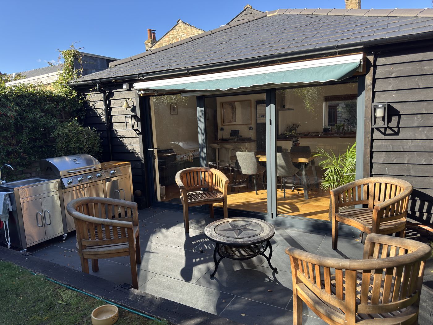 Finished extension with black timber cladding, sliding doors, tiled patio and awning
